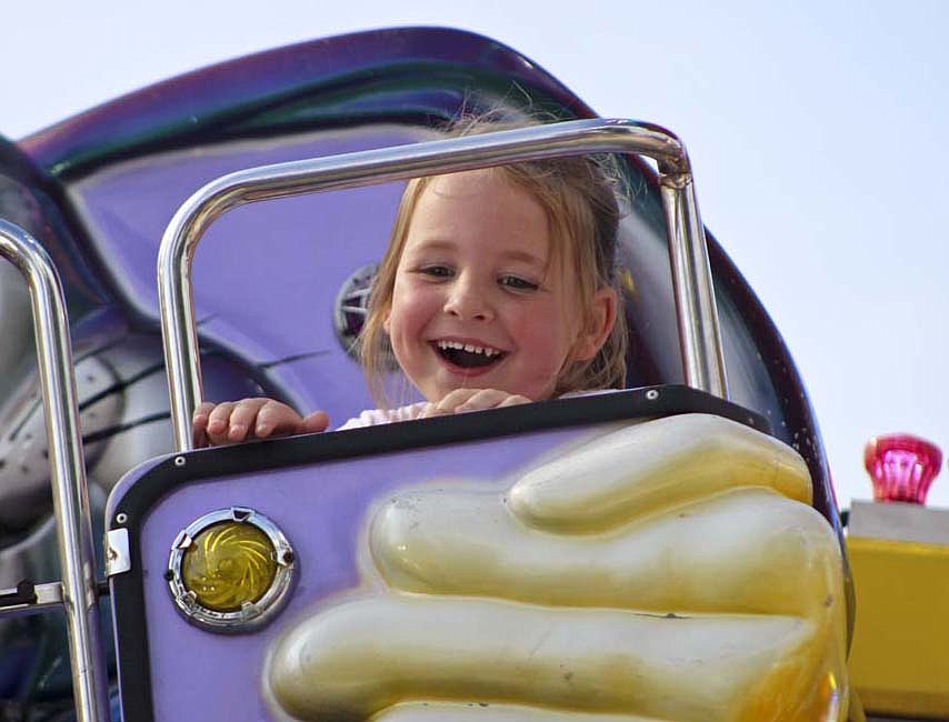 It was a busy night on the midway Wednesday at the Jay County Fair, and the 4-H horse and pony show followed throughout the day Thursday. Pictured, Margot Moore, 4, grins at her family Wednesday while riding the Funny Bunny on the midway. (The Commercial Review/Bailey Cline)