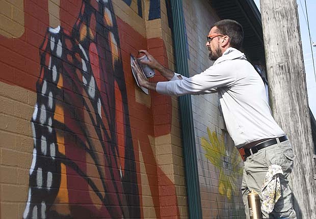 Zach Medler puts some finishing touches on the R in the word Portland this morning while working on his mural on the north side of Community Resource Center in Portland. The City of Portland in April received a $10,000 grant from Indiana Destination Development Corporation for the mural as part of more than $400,000 in funding awarded for IN Indiana Public Art Activation projects. It is the second Portland mural for Medler, a Geneva native and former Arts Place employee, as he also painted the Portland Rotary Club mural on the south side of the J&P Plating Building. (The Commercial Review/Ray Cooney)