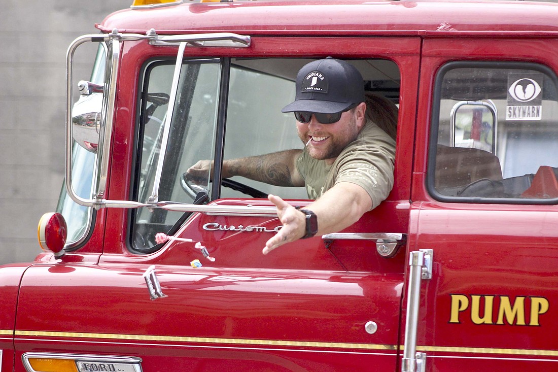 Firefighter Drew Lloyd tosses candy out to paradegoers along High Street in Redkey during the town’s Gas Boom Days parade Saturday. (The Commercial Review/Bailey Cline)