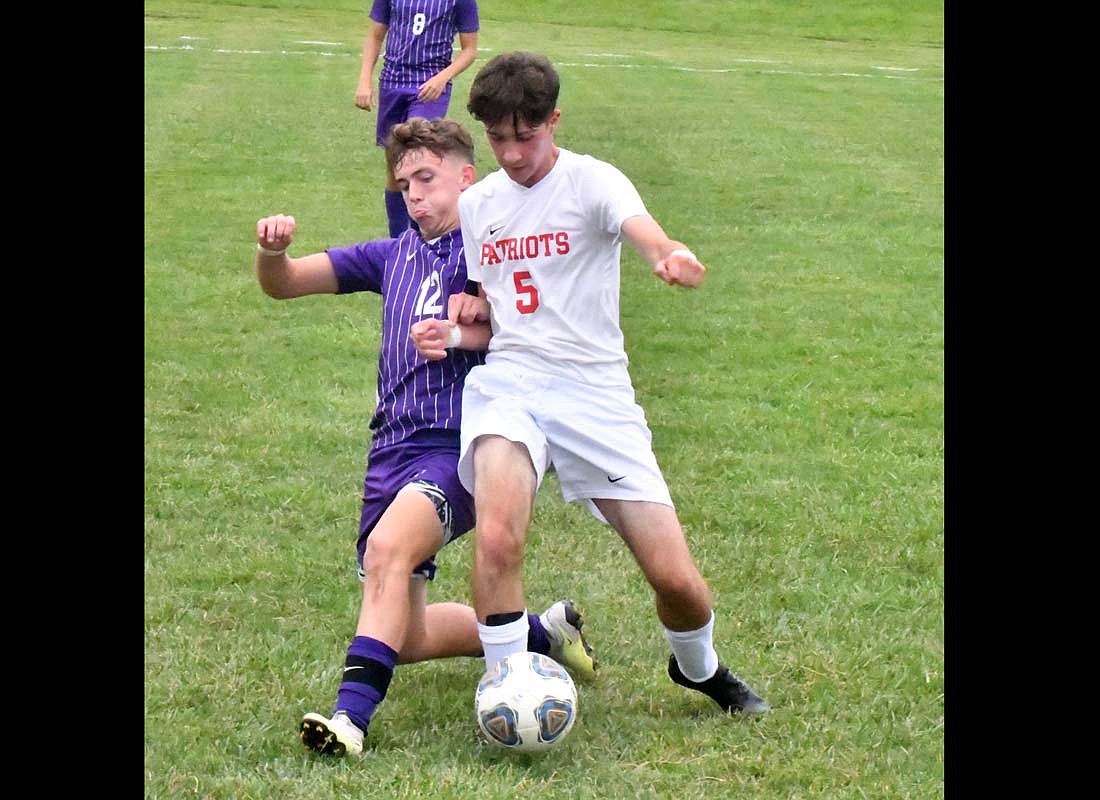 Oskar Alart Mateo (5), an exchange student from Spain, uses his body to shield the hall from Muncie Central’s Brady McNabb (12) during the Jay County High School boys soccer team’s match on Tuesday. The Patriots lost the game 5-2, scoring both of their goals in the second half. (The Commercial Review/Andrew Balko)