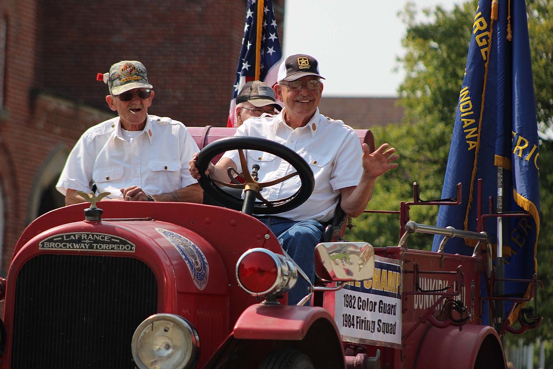 Members of Dunkirk’s American Legion Post 227 wave to children watching the Montpelier Jamboree parade as floats made their way down Adams Street on Saturday. (The Commercial Review/Bailey Cline)