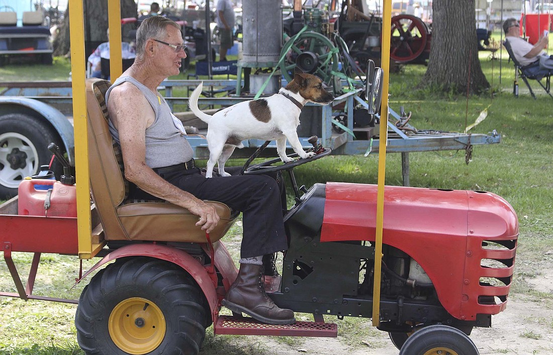 Merrill Butterfield and his dog, Jack, cruise through the northern portion of the fairgrounds Wednesday in their custom-built tractor. Butterfield, a Warren resident, has been visiting the show for more than 50 years. (The Commercial Review/Bailey Cline)