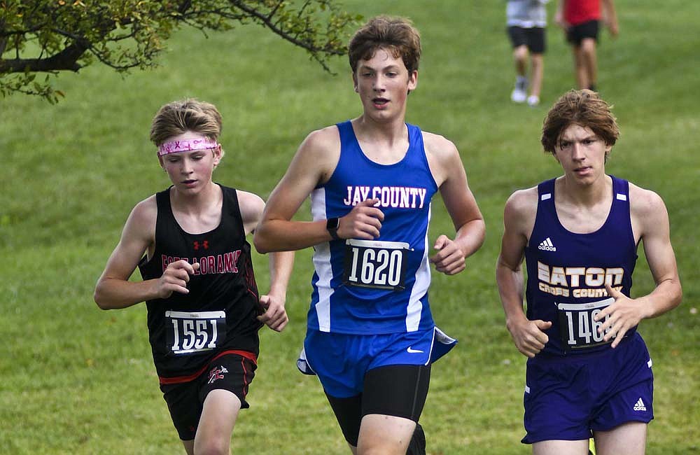 Jay County High School sophomore Max Klopfenstein runs between Theodore Gaier (1551) of Fort Loramie and Michael Fomin (1464) of Eaton during Saturday’s Celina Rotary Invitational at Wright State University – Lake Campus. He was the No. 4 runner for the Patriots as he finished 61st overall in 21 minutes, 5.67 seconds. (The Commercial Review/Ray Cooney)