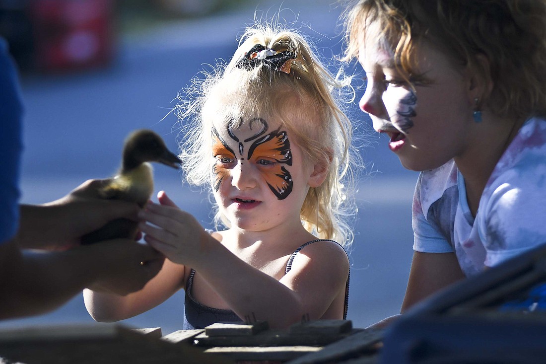 Four-year-old JoJo Bentz and 8-year-old Kenna Cramer (right), both of Portland, make friends with a duckling during Friday’s fall festival in Dunkirk. The event at the former Webster Depot, now home to Living in Joy, featured various vendors and activities. (The Commercial Review/Ray Cooney)