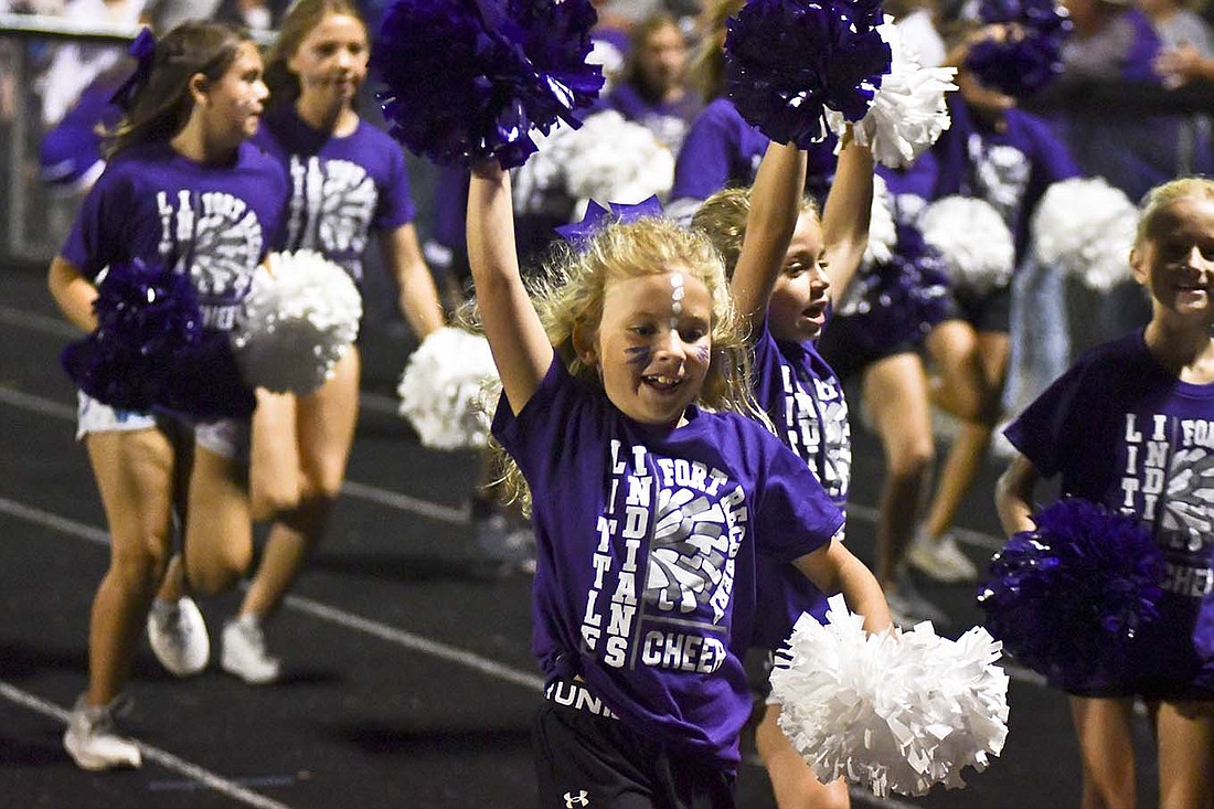 Participants in Fort Recovery High School’s Little Indiana cheerleading clinic run along the track Friday night after cheering along the sidelines during the Indians’ football game against Minster. (The Commercial Review/Andrew Balko)