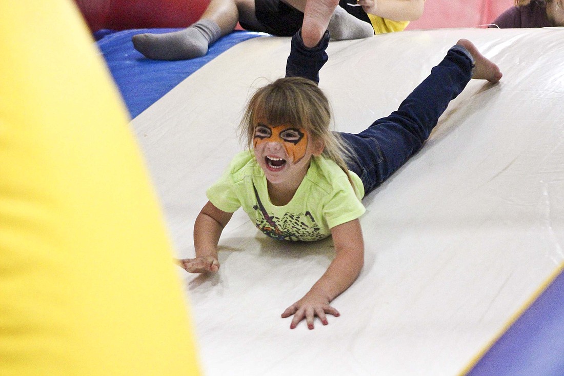 Kaelyana Castillo, 5, slides down the inflatable slide inside Jay Community Center during Hopefest activities on Saturday. The event offered informational booths, prizes, inflatable bounce houses and slides, a petting zoo and other activities for local families. (The Commercial Review/Bailey Cline)