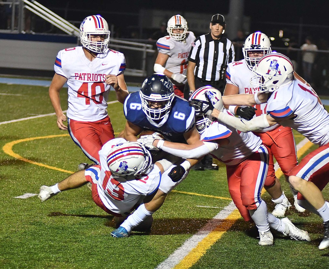 Jay County High School’s Lucas Strait (13) and Garrett Bennett work together to take down Woodlan's Drew Fleek as a swarm of other Patriots seek to join in on Friday night. The defense strung together three stops to finish out the game on a 20-0 scoring run for a 34-29 victory over the Warriors. (The Commercial Review/Andrew Balko)