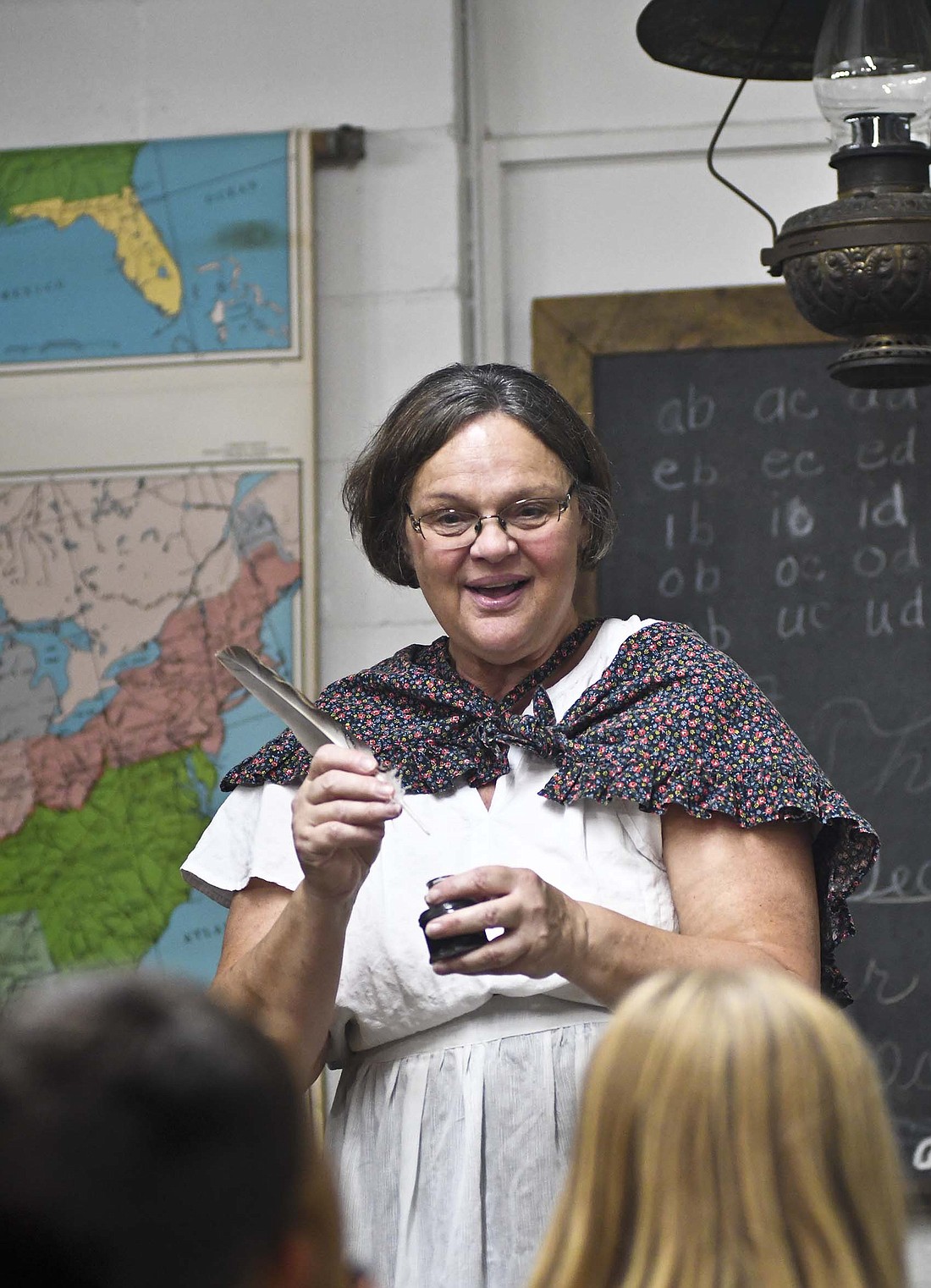 Former Jay School Corporation teacher Jodi McKee shows visitors to the Heritage Festival a quill and inkwell set Sunday afternoon. The annual festival at Jay County Historical Museum featured music, food, historical reenactments and a variety of other activities. (The Commercial Review/Ray Cooney)