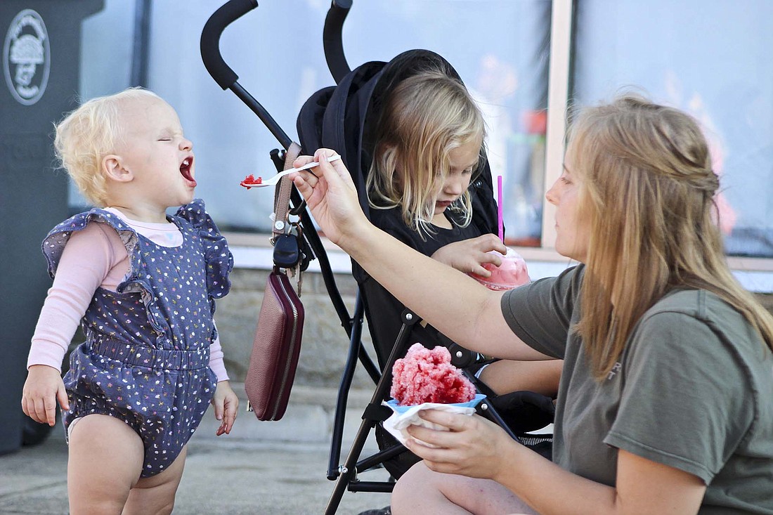 Jay County was bustling with activity over the weekend. Pictured above, 1-year-old Heidi Cline readies for a spoonful of shaved ice from mother Haley Cline on Saturday at the Portland Main Street Fall Festival. Below, Patricia Boelte of Torch Time in Anderson uses a torch to heat up a chain she was working on at one of the various glass-related booths at the reincarnation of Glass Days in Dunkirk. (The festival had been dormant since 2019.) (The Commercial Review/Bailey Cline)