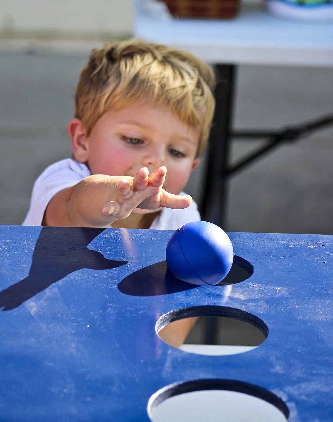 Milo Wellman, 2, rolls a ball as part of a game offered at The Rock Church’s stand Saturday during Portland Main Street Fall Festival’s activities. (The Commercial Review/Bailey Cline)