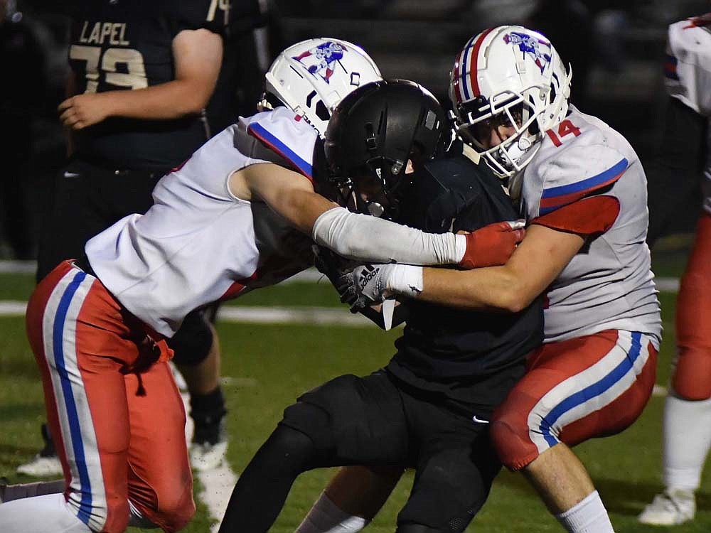 Jay County’s Lucas Strait (left) comes in to help Bryce Wenk (14) take down Lapel freshman Jack Miller in Friday night’s 28-7 loss. (The Commercial Review/Andrew Balko)