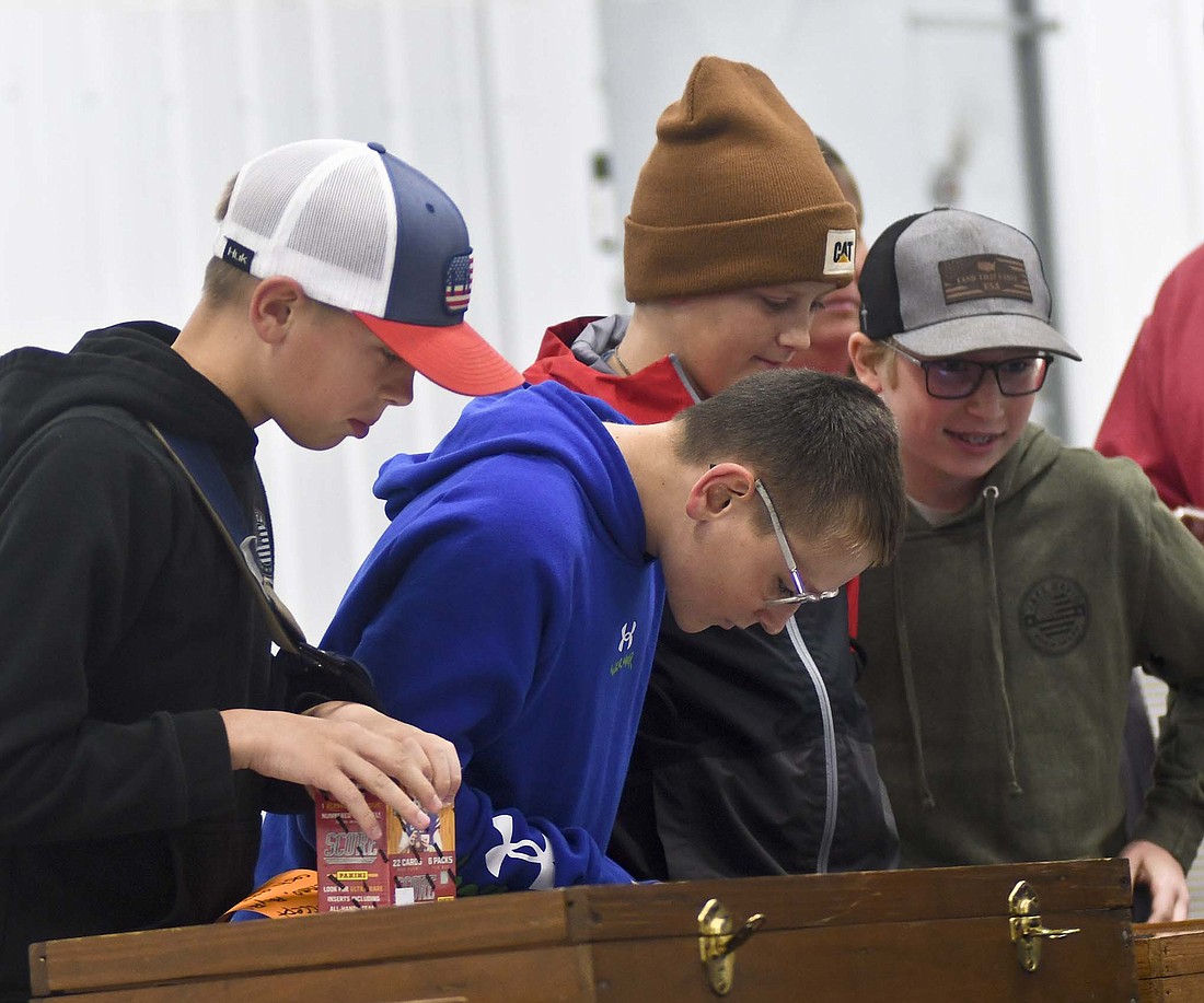 Jade Westgerdes, 12, Roman Clamme, 12, Murphy Link, 11, and Fletcher Post, 11, check out a display of sports cards Saturday during the inaugural Jay County Fair Board Cards, Comics, Coins & Collectibles Show in the Bubp Building at Jay County Fairgrounds. The boys spent some time playing a dice-roll game to win cards and Post purchased a Justin Fields football card for one of his buddies. “I know how much you wanted it,” he told his friend, a Chicago Bears fan. (The Commercial Review/Ray Cooney)