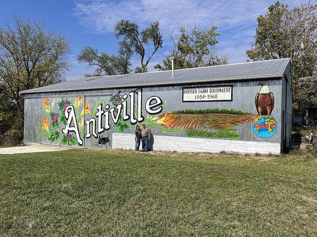 Marie McKinley, pictured with her father R.D., completed, for now, her mural at the northwest corner of U.S. 27 and county road 400 North last week. (She plans to add a Case tractor to the mural in the spring.) The west side of the mural depicts ditch lilies and raspberries, which are common to the area, while the east side is a tribute both to Houser Farm Equipment, the Case dealership her father R.D. Houser and grandfather Raymond Houser ran from 1954 through 1968, and the Tri-State Gas Engine and Tractor Association.
“In a way, I’m kind of proud of it,” said R.D. Houser. “In another way, I’m kind of humbled because I never thought anything like this would happen.” (The Commercial Review/Ray Cooney)