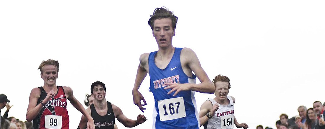 Sophomore Joseph Boggs of Jay County High School crosses the finish line ahead of a pack of four runners to finish fourth at the sectional race at Taylor University Oct. 14. (The Commercial Review/Ray Cooney)