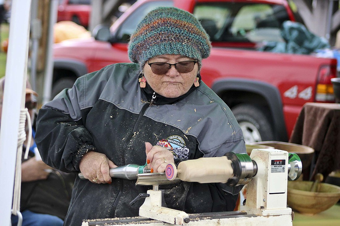 Teresa Kelly works on her lathe Saturday at Pennville Park. The rural Portland resident sold various wooden bowls and other handcrafted items during the Pennville Pumpkin Festival. (The Commercial Review/Bailey Cline)