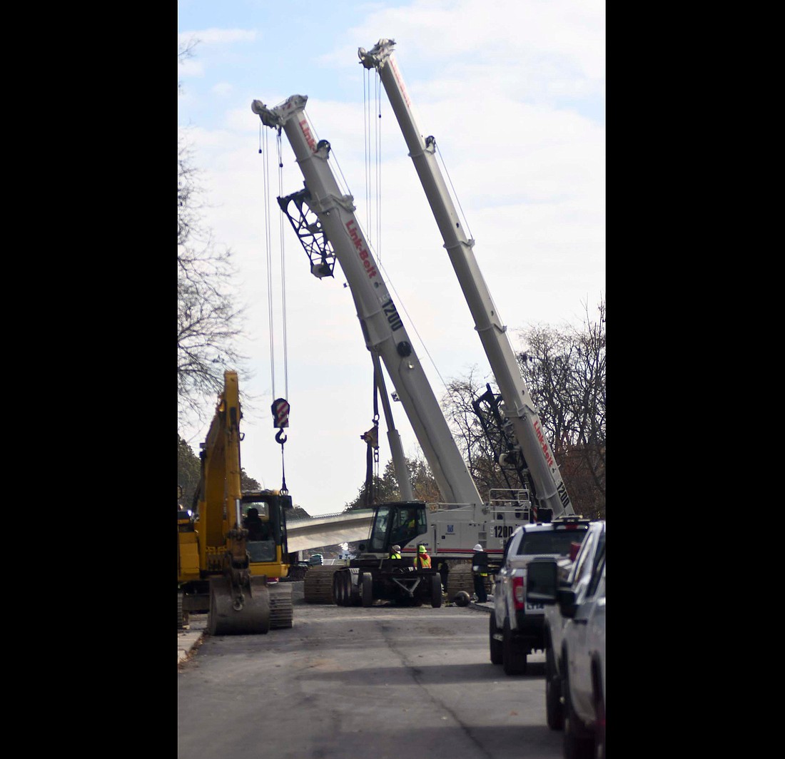 Crews use two cranes Tuesday morning to move pieces into place as part of the bridge replacement project on Indiana 26 (Water Street) over the Salamonie River on the east side of Portland. (The Commercial Review/Ray Cooney)