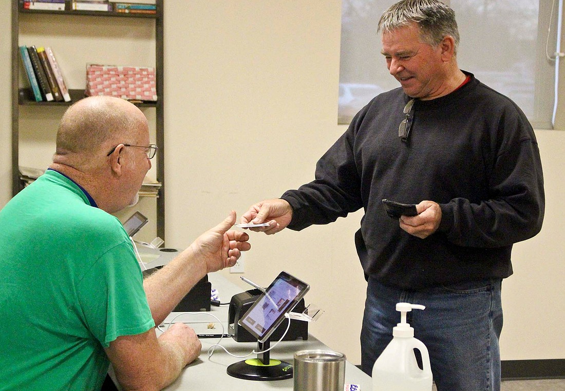 Rick Shannon, right, hands over his driver’s license before voting Tuesday morning at Jay Community Center. This year’s municipal election includes contested races for mayor in Dunkirk and Portland. For election results, visit thecr.com. (The Commercial Review/Bailey Cline)