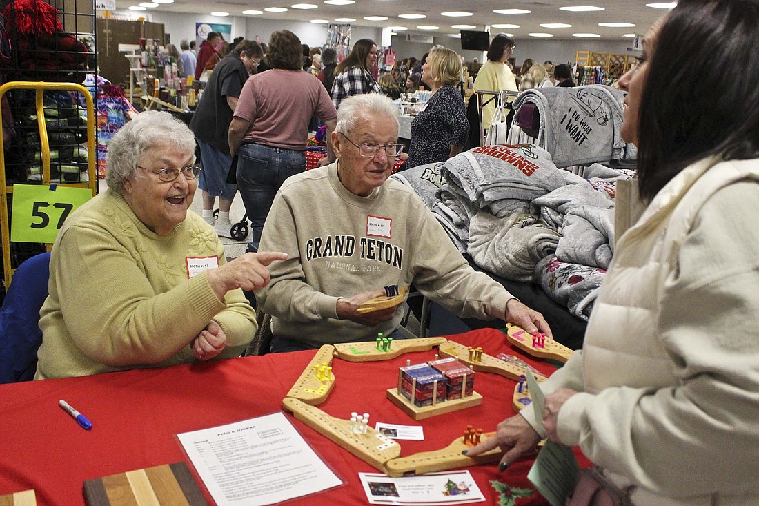 Joan and Galan Gray of Keystone explain their homemade board game, “Pegs and Jokers,” to a woman visiting the Delts’ Holiday Crafts and Gift Show on Saturday morning at Jay County Junior-Senior High School. (The Commercial Review/Bailey Cline)