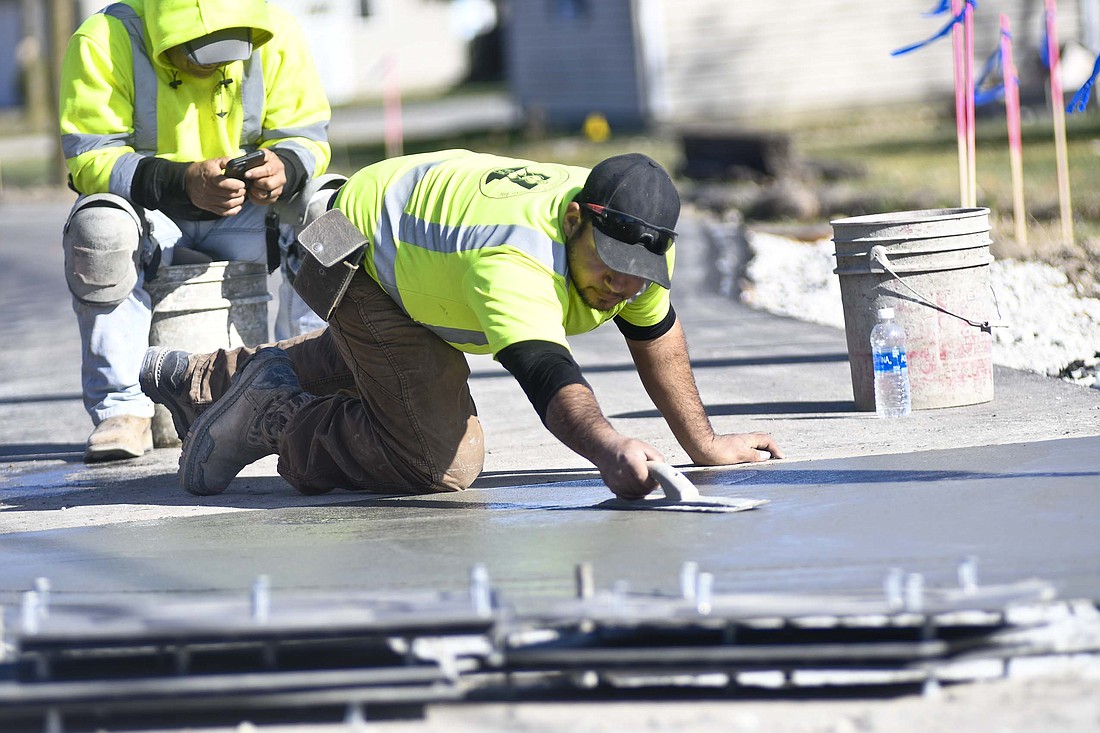 Jesus Medina of Edward and Jones smooths a section of sidewalk shortly after noon today as part of the new walking path along the east side of Blaine Pike at its intersection with Green Park Drive in Portland. The trail runs from near Bittersweet Lane to near the train tracks just south of Water Street. (The Commercial Review/Ray Cooney)