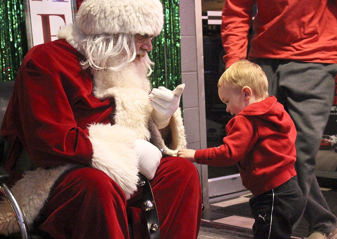 Santa greets one of his young visitors Monday evening at Glass Capital Chrysler in Dunkirk. His visit to the dealership was part of the city’s Feel the Warmth of Christmas celebration. (The Commercial Review/Bailey Cline)