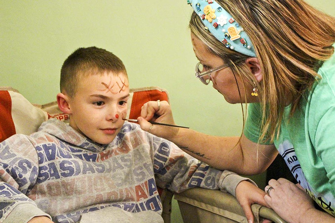 Kenci Grayson, right, paints 9-year-old Kalvin Hardwick’s face Monday at Living in Joy during Dunkirk’s Feel the Warmth event. (The Commercial Review/Bailey Cline)