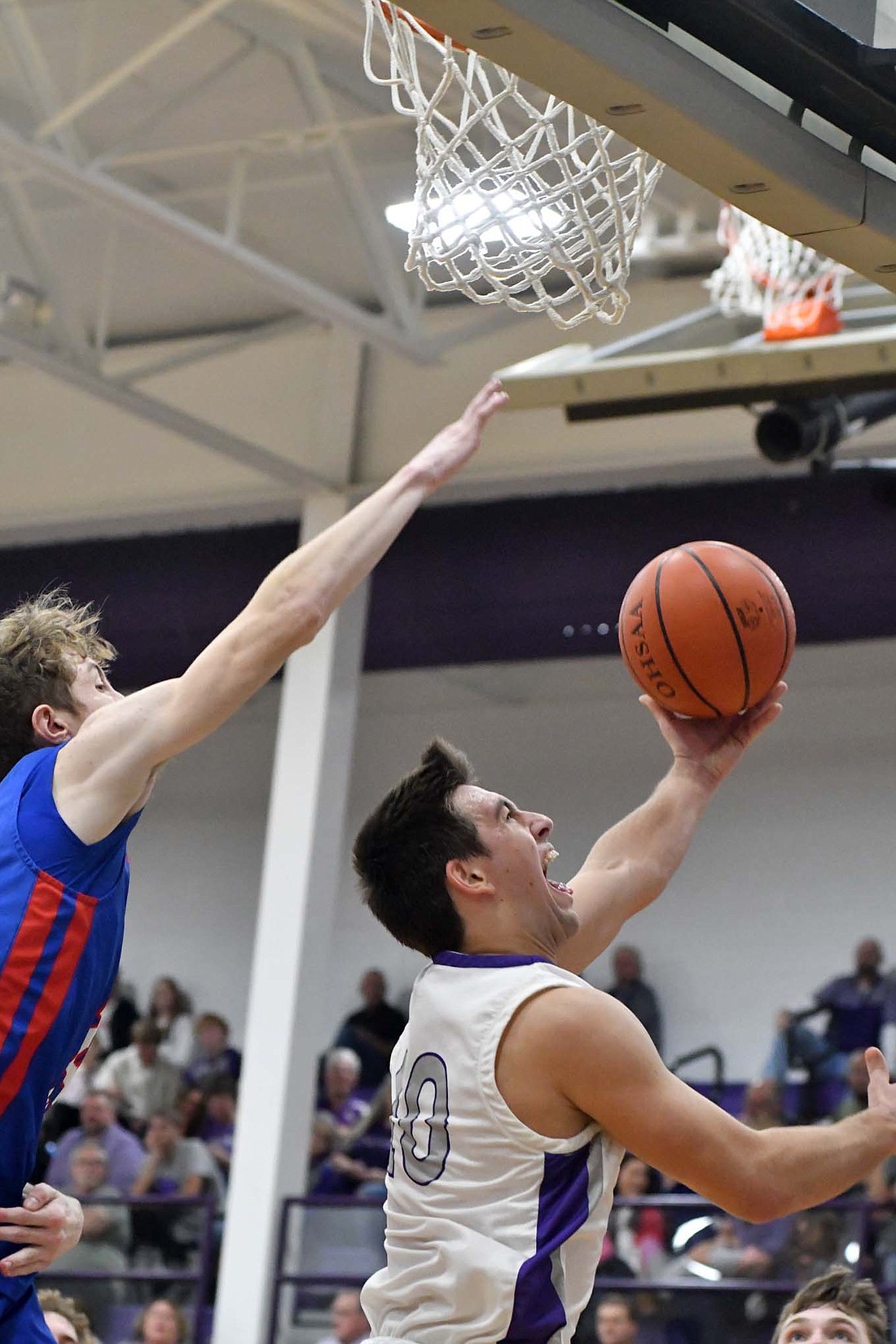 Troy Homan, a senior on the Fort Recovery High School boys basketball team, goes up for a left-handed, reverse layup as Jay County’s Ben Crouch tries to block it from behind in the first half of the Indians’ 38-31 victory on Saturday. It was the only hoop for the Indians in the first quarter, but they stormed back with an 18-0 run starting in the second period. (The Commercial Review/Andrew Balko)