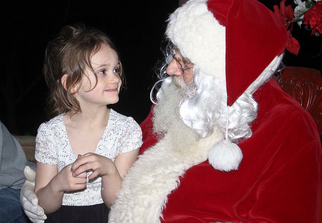 Aiyana Morton, 5, tells Santa Claus what she wants for Christmas at the gazebo Saturday in downtown Redkey. Santa made his annual visit to the town over the weekend. (The Commercial Review/Bailey Cline)