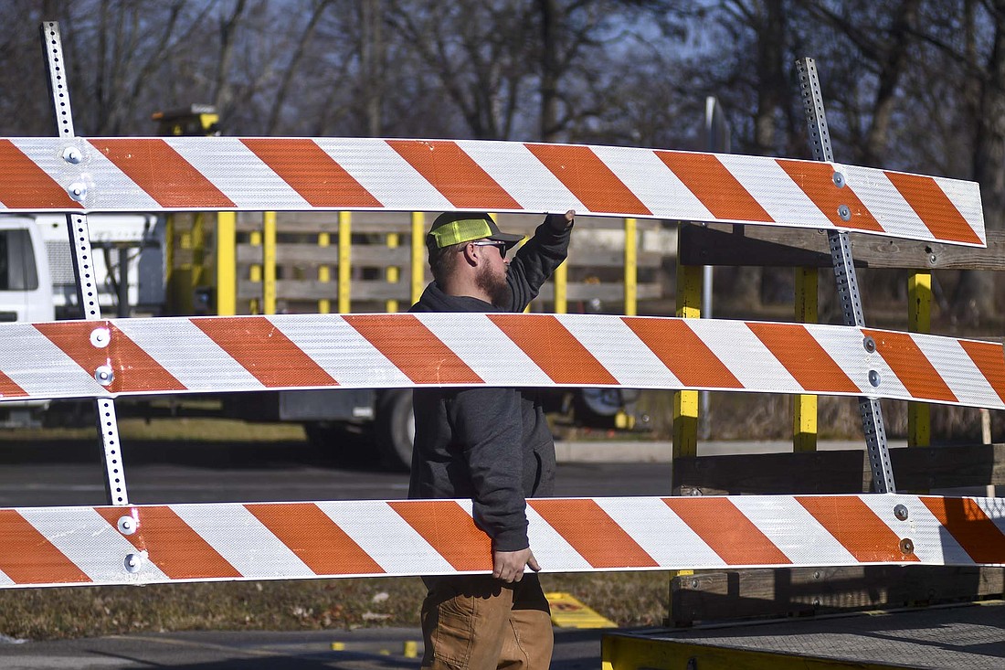 An employee from Indiana Sign & Barricade removes one of the barricades late Wednesday morning from the west side of the Indiana 26 (Water Street) bridge over the Salamonie River on the eastern edge of Portland. The bridge was expected to open Wednesday afternoon. It has been closed for construction of a new concrete bridge replacing the former steel truss bridge since late June. (The Commercial Review/Ray Cooney)