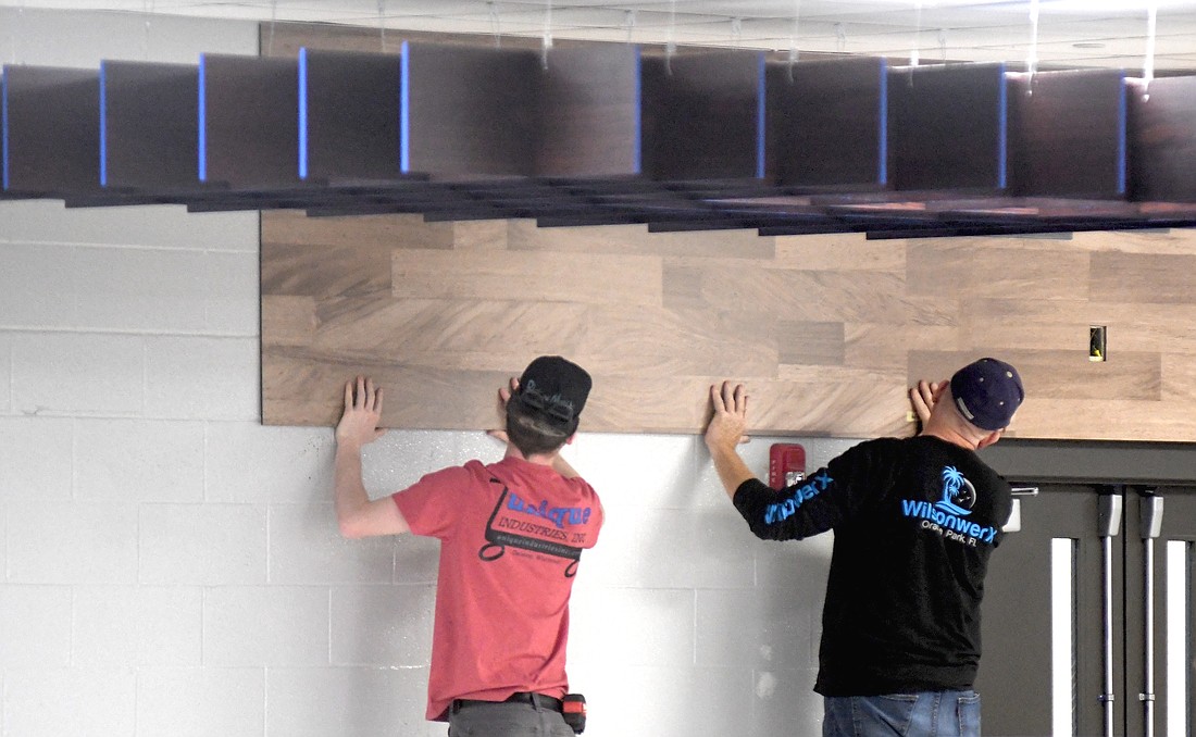 The commons at Jay County Junior-Senior High School is in the process of renovations. Pictured, workers from furniture manufacturing firm Palmer Hamilton install new wall coverings. The upgrades to the commons, which are scheduled to be complete when students return next week, features a new design with a focus on a more collegiate/retail look, including seating with booths and bar-height tables of various shapes and individual seating. A ribbon-cutting ceremony is scheduled for 10 a.m. Wednesday. (The Commercial Review/Ray Cooney)