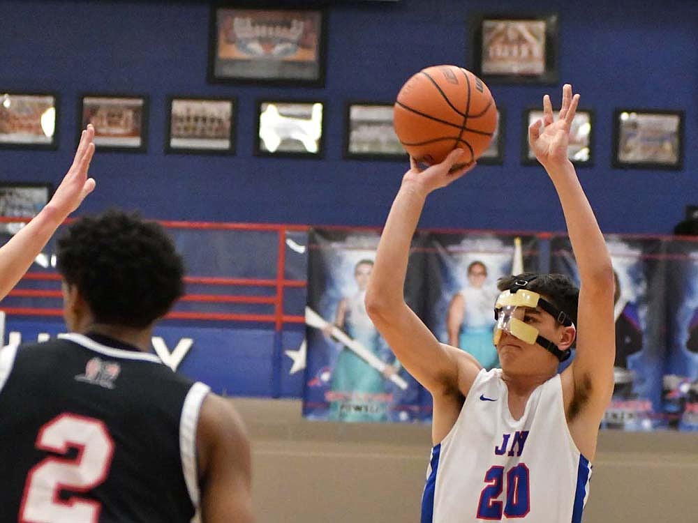 .Jay County High SchoolÕs Liam Garringer puts up a 3-point shot during a 69-60 loss to Class 2A No. 3 Bishop Luers on Tuesday. Despite having to wear a mask to prevent stiches from being opened up, the JCHS senior went off for 22 points, including 14 in the fourth quarter. (The Commercial Review/Andrew Balko)