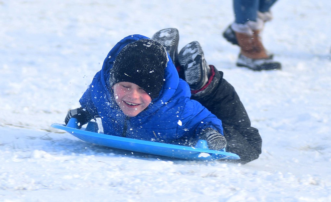 Snow sprays in the face of Phynox Storie while sledding with friends Friday afternoon at Hudson Family Park in Portland. A few inches of snow fell between late Thursday and Friday morning. Some additional light snow is expected today, with patchy blowing snow Monday night followed by rain for the next several days. (The Commercial Review/Ray Cooney)