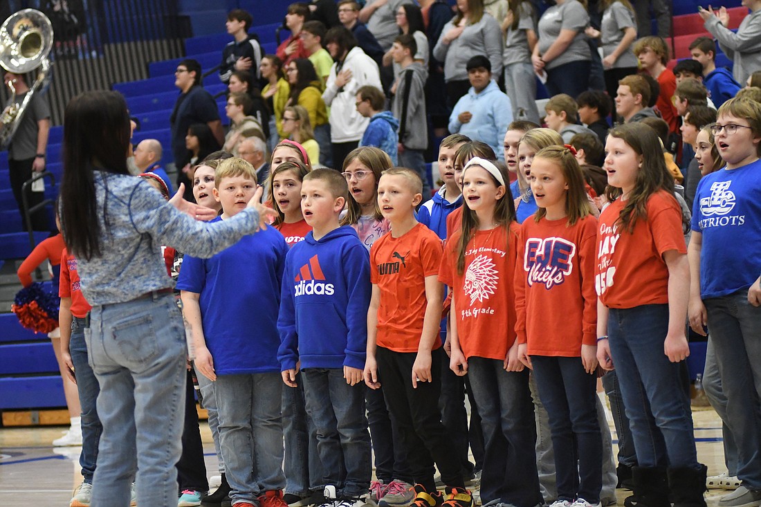 The East Jay Elementary School choir, under the direction of Jan Rittenhouse (left) performed the national anthem Friday night prior to the Jay County High School boys basketball team’s win over the South Adams Starfires. (The Commercial Review/Ray Cooney)