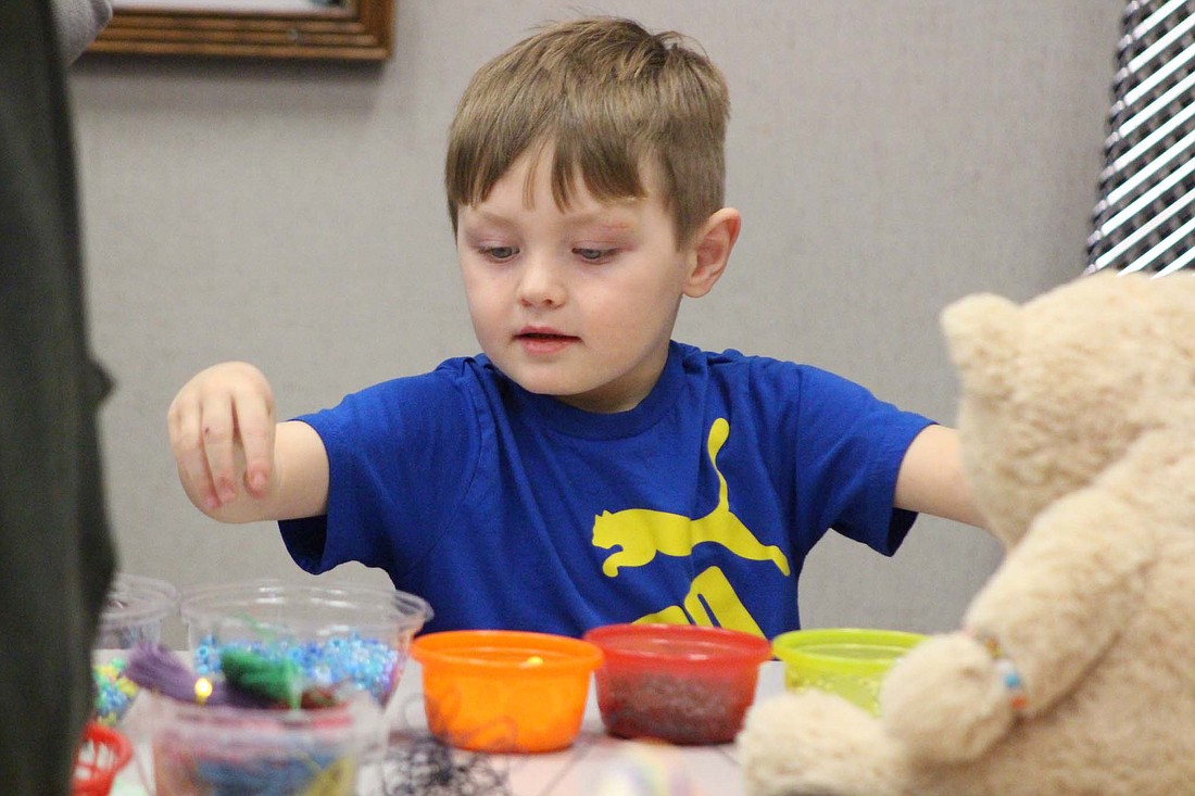 Four-year-old Eli Ferner selects beads for a friendship bracelet Tuesday at Jay County Public Library. Ferner created a bracelet for his stuffed bear and for himself as part of the event, which offered crafts and story time for children with their toys. (The Commercial Review/Bailey Cline)