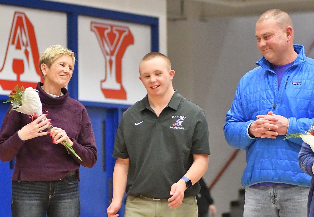 Jay County High School senior Luke Vormohr (middle) was honored during the Jay County boys basketball team’s senior night for his work as the team’s manager. Pictured, mother Marcie, Luke and father Frank listen to coach Jerry Bomholt’s speech about Luke and what he has meant to the program. (The Commercial Review/Andrew Balko)