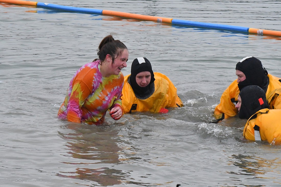 Paige Finch laughs with Portland firefighters as they search for her glasses at Splashin’ with a Passion: Peggy’s Plunge on Saturday. Finch dunked her head under the water as part of the polar plunge, causing her glasses to fall off. Volunteer firefighter Chris Elmore found them after a couple of minutes of searching. (The Commercial Review/Andrew Balko)