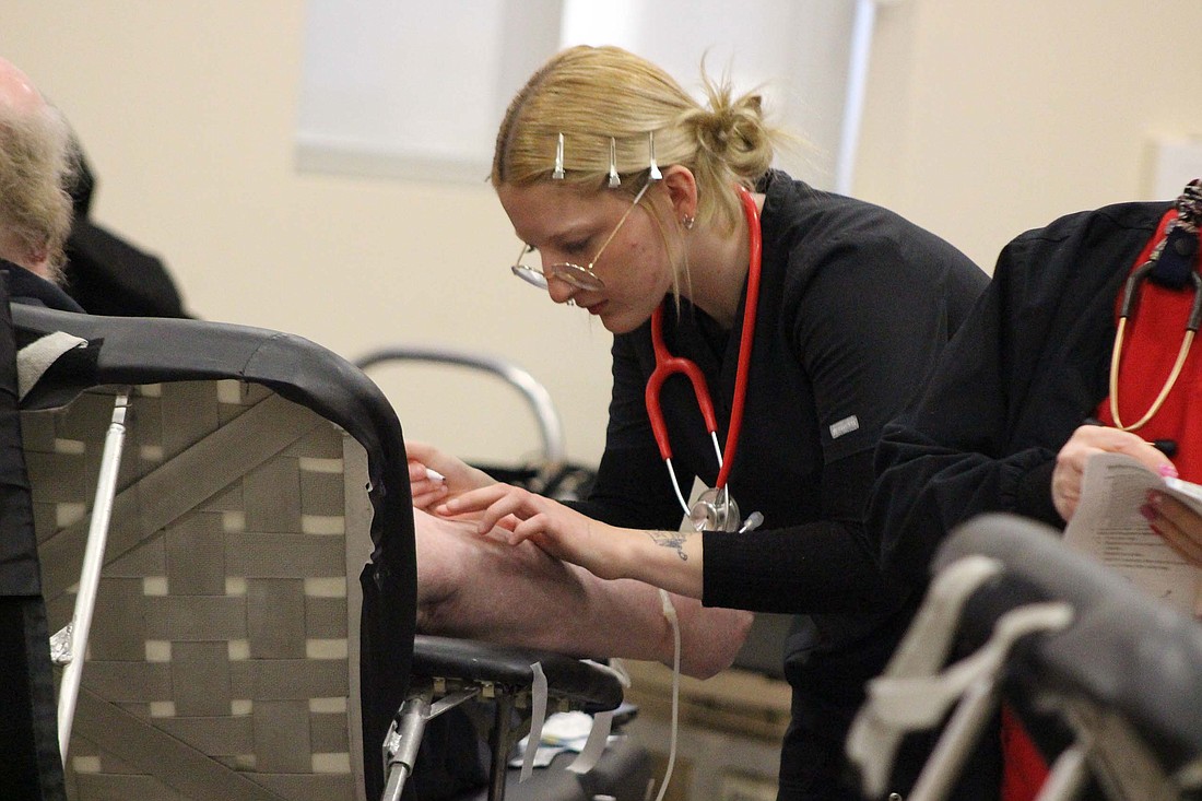 American Red Cross volunteer Sidney Stewart marks a donor’s arm before injecting a needle into him during the blood drive Tuesday at Jay Community Center. (The Commercial Review/Bailey Cline)