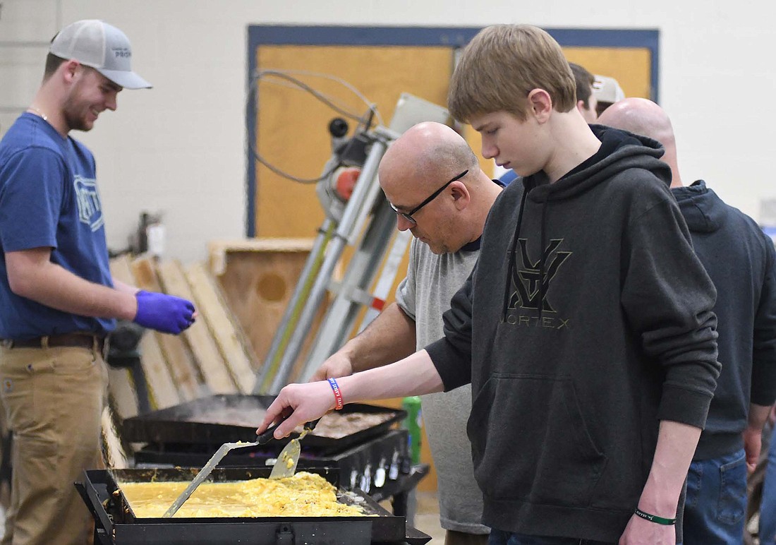 Jay County FFA member Max Dues (foreground) and advisor Matt Slavik work together to cook eggs Thursday morning for the staff brownie breakfast at Jay County Junior-Senior High School. The chapter is holding its Blue and Gold/FFA Spirit Day today and had a truck drive-in this morning with awards for dirtiest, rustiest and best of show. (The Commercial Review/Ray Cooney)