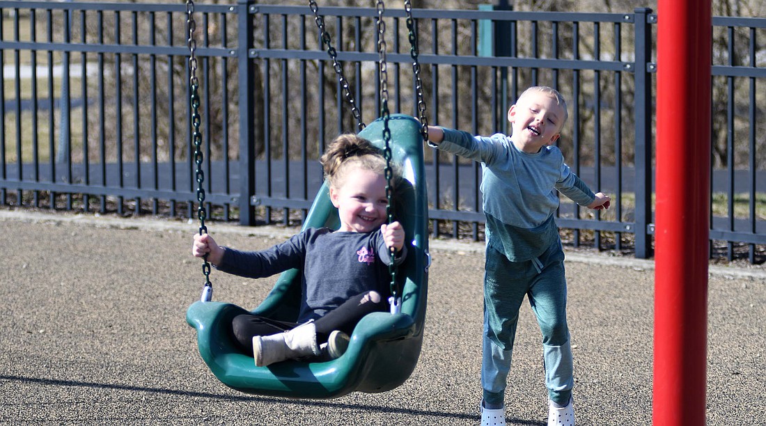 Five-year-old Ezekiel Hines pushes 4-year-old Arieghia Sanchez on the swings late Monday morning at Hudson Family Park in Portland while taking advantage of the unseasonably warm temperatures. Temperatures have been on a roller coaster recently with snow followed by a high of 20 degrees Feb. 17, highs in the 50s and 60s last week, snow and a high in the 20s again Saturday and then a high in the upper 60s Monday. (The Commercial Review/Ray Cooney)