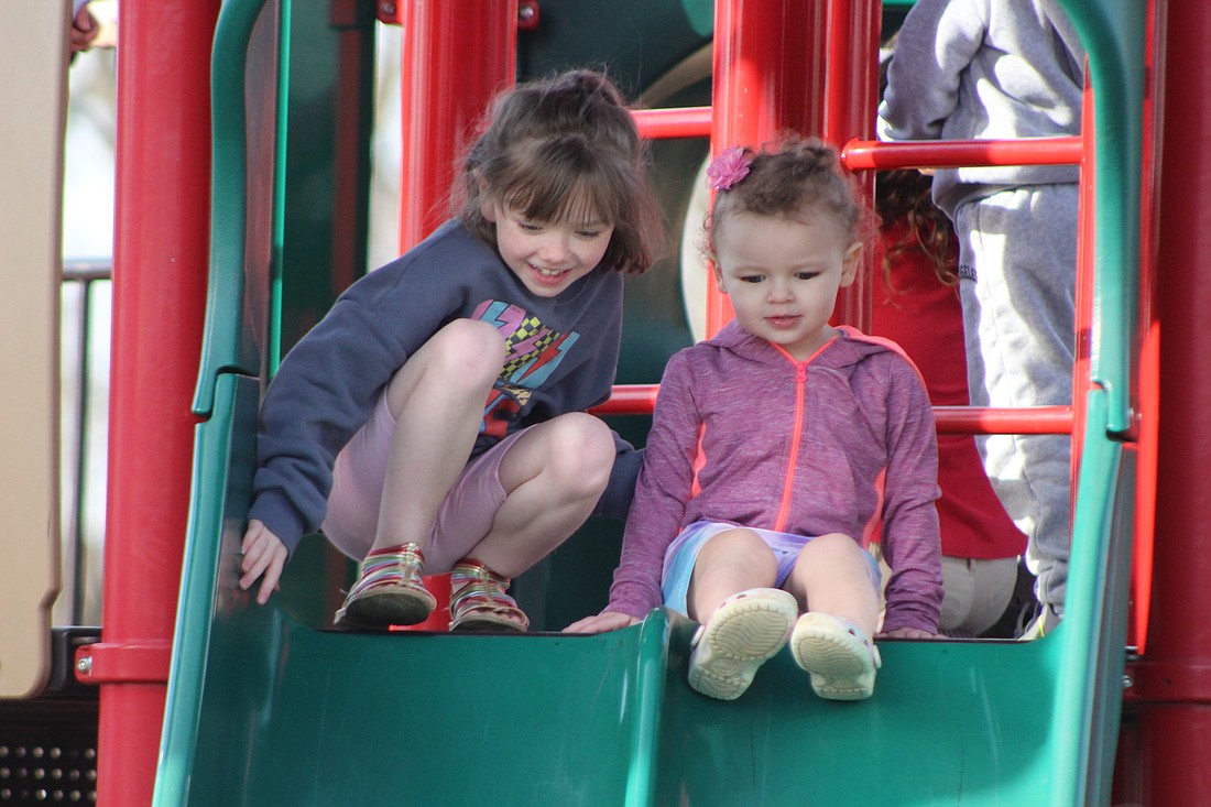 Seven-year-old Bonnie Wooton and 2-year-old Joey Chapman prepare to go down the slide Tuesday at Hudson Family Park. Temperatures in Jay County jumped to the 60s Tuesday afternoon, drawing several residents outside to enjoy the warmer weather. (The Commercial Review/Bailey Cline)