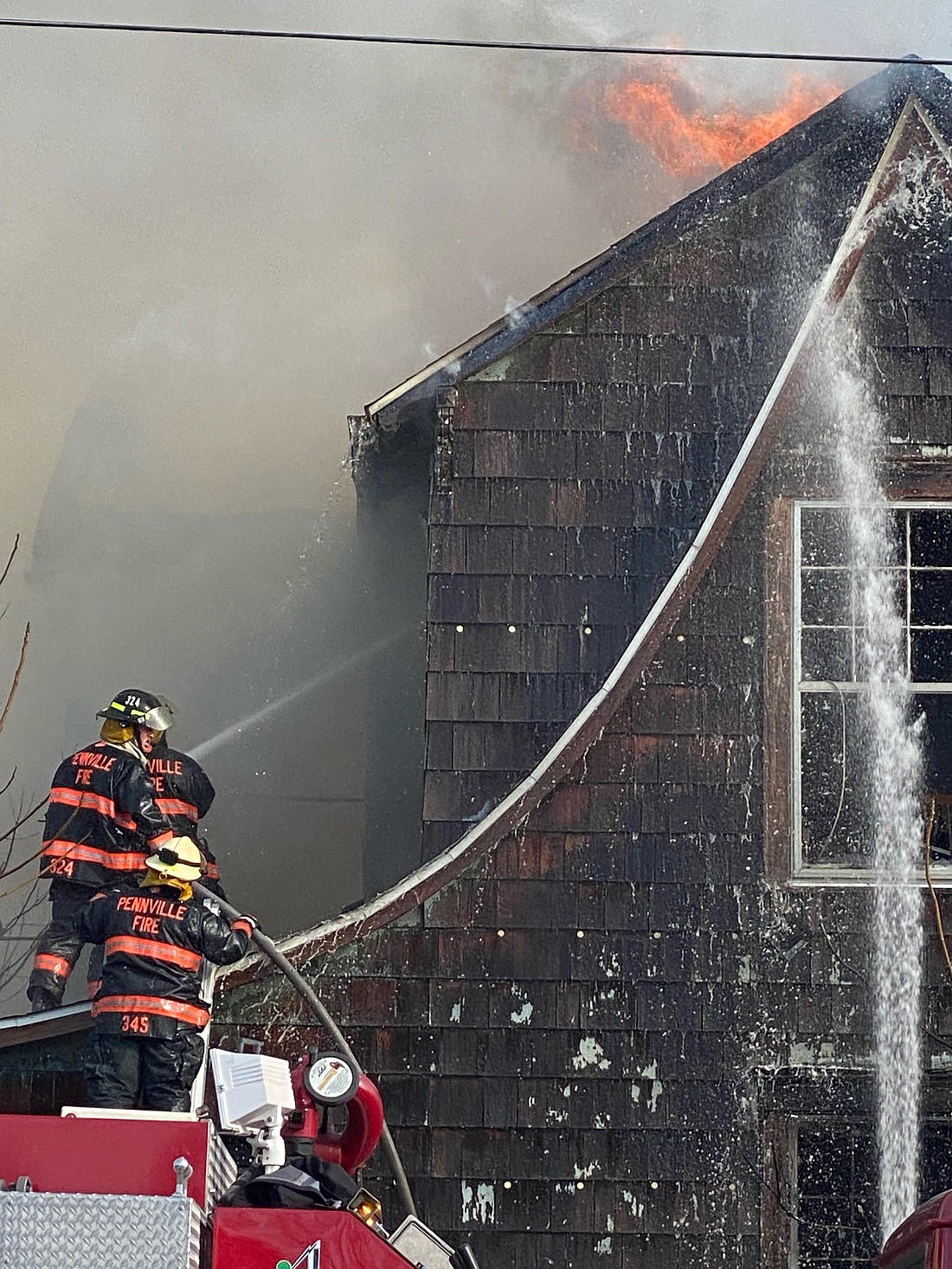 Pennville firefighters spray water on a house while fighting a fire at 617 S. Main St., Dunkirk, on Tuesday afternoon. They joined firefighters from Redkey, Albany and Eaton in assisting Dunkirk Fire Department at the scene. The fire was under control by about 6 p.m., but the house was destroyed. For details, see Capsule Reports on page 2. (Special to The Commercial Review/Sam Thomas)