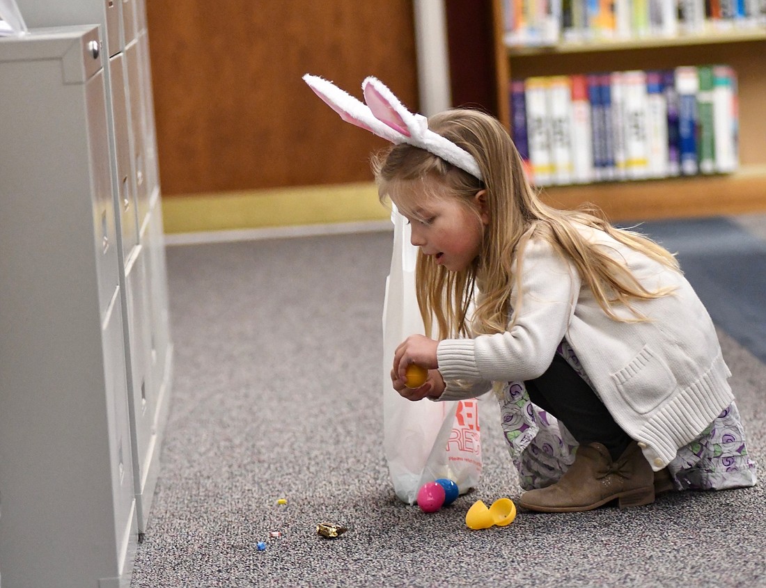 Four-year-old Gracie Sanderson checks out some of the items in the eggs she found Wednesday morning during an Easter egg hunt at Jay County Public Library in Portland. Children were allowed to find 15 eggs apiece that were scattered throughout the library and also participated in various Easter-themed crafts. (The Commercial Review/Ray Cooney)