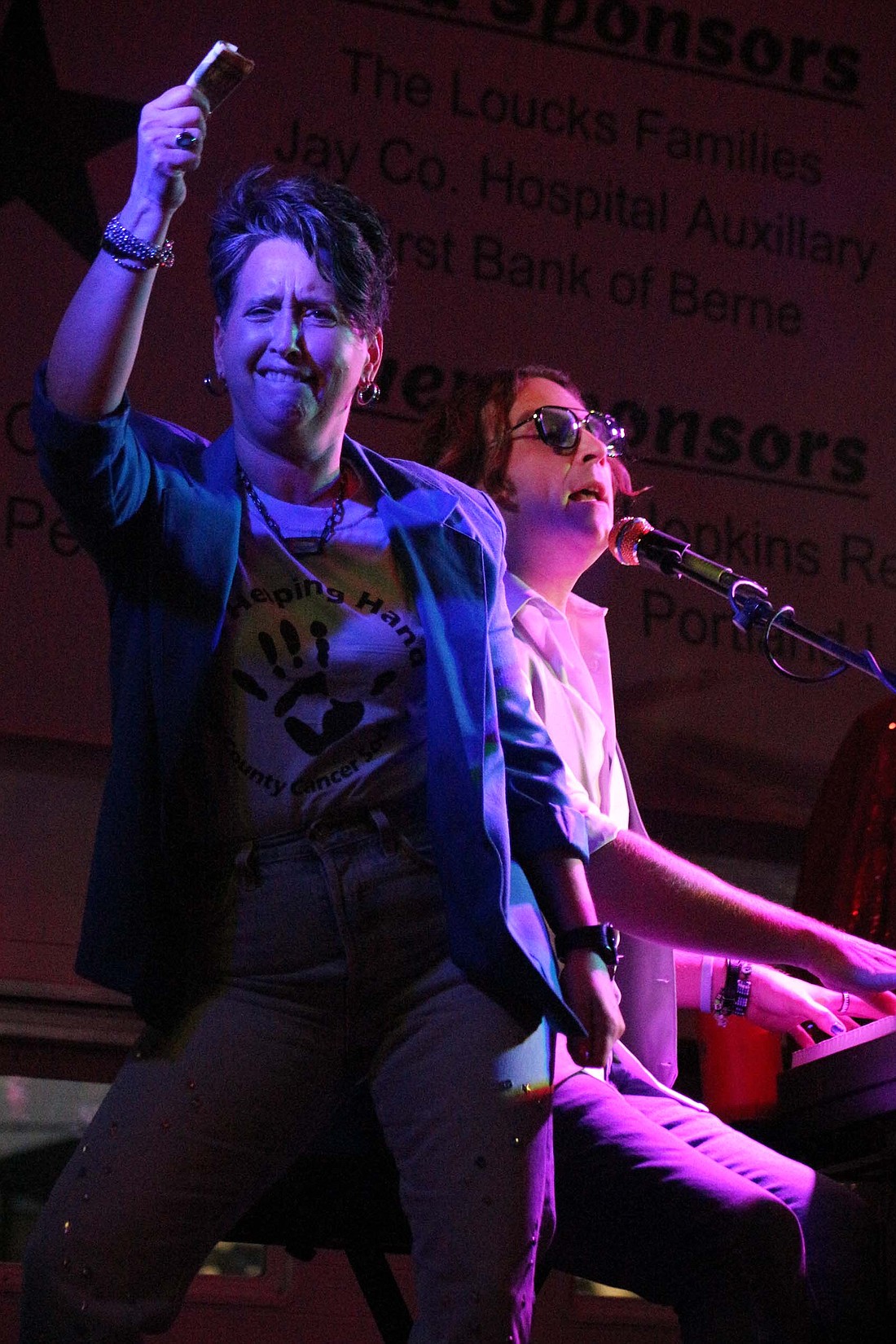 Tisha Gierhart brings up a song request and tip to Dueling Pianos International player Dan Louisell during Jay County Cancer Society’s benefit show Saturday at Jay County Fairgrounds. (The Commercial Review/Bailey Cline)