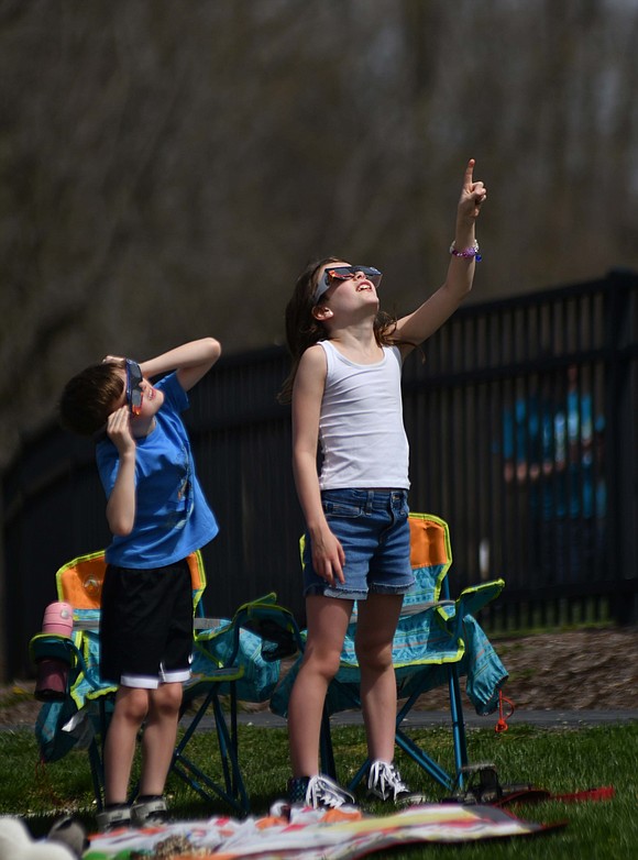 Residents and visitors gathered at various locations across Jay County to watch the solar eclipse. Pictured, Dunkirk residents, from left, Alyzah Willoughby, 7, Aubrey McClain, 10, and Brionna Walradth, 10, gaze into the sky using their eclipse glasses from atop the wooden train in Webster Depot Park during a festival to celebrate the event. The moon completely blocked the sun for a period of about 4 minutes. (The Commercial Review/Andrew Balko)