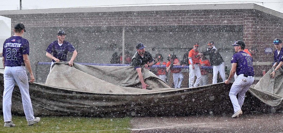 Members of the Fort Recovery High School baseball team, along with the Versailles baseball coach quickly put a tarp over home plate after hail started raining down during Tuesday's game. The game was suspended in the top of the fifth inning and will be picked up at a later date. (The Commercial Review/Andrew Balko)