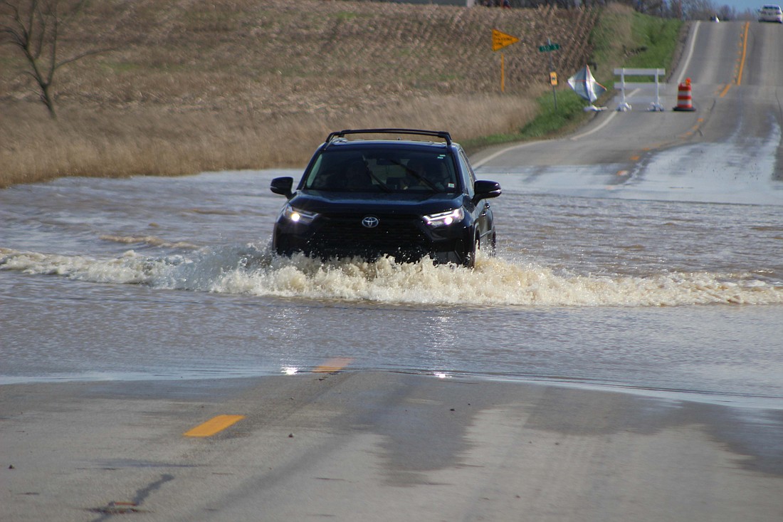 Various roads and areas in Jay County were flooded Friday, the result of more than 7 inches of rainfall in the last few weeks. Pictured above, a Toyota driver passes through a body of water Friday along Indiana 1 between county roads 100 and 150 South about four miles north of Redkey. Jay County issued a flood warning through 5:49 p.m. today. (The Commercial Review/Bailey Cline)