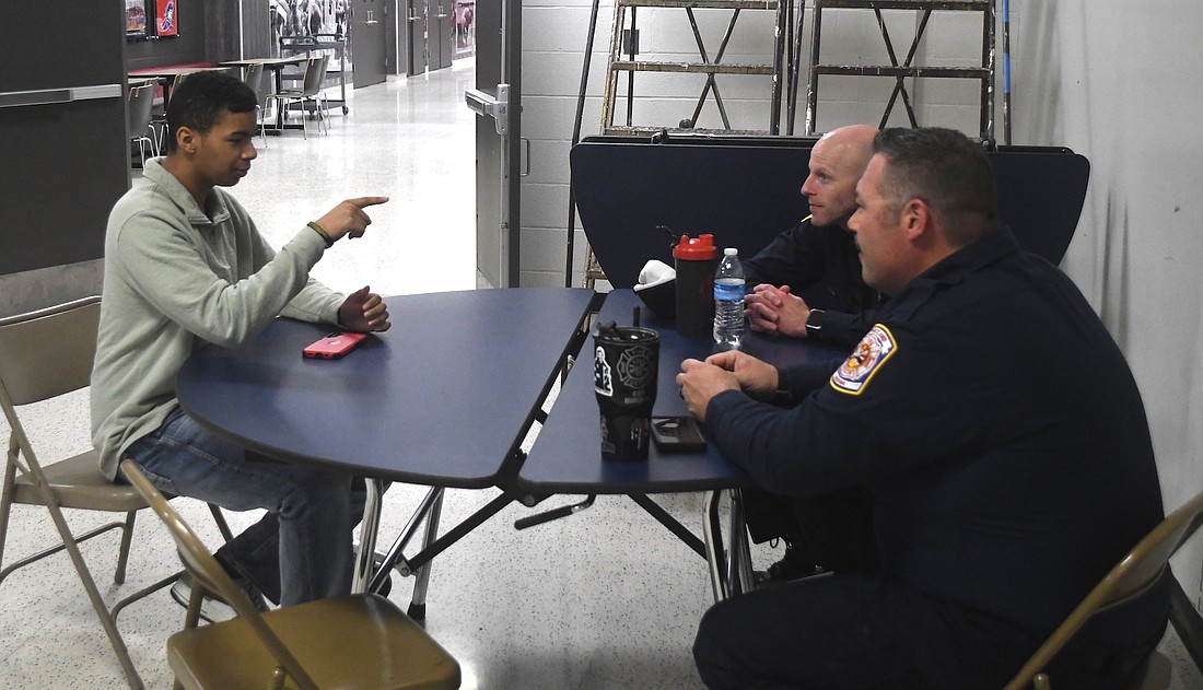 Student Alex Doll gestures while chatting with Dustine Hilfiker (foreground) and Mitch Southworth (background) of Portland Fire Department during Interview Day at Jay County Junior-Senior High School. (The Commercial Review/Ray Cooney)