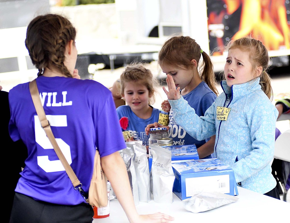 Nine-year-old Rebecca Schulze explains some of her products to customers while selling Saturday during Psi Iota Xi sorority’s Chicks on the Bricks event on the brick section of Wayne Street in Fort Recovery. She and her sisters — Charlotte, 5, and Jennifer, 7 — were selling a variety of items including freeze-dried Skittles, cookies, bracelets and necklaces. (The Commercial Review/Ray Cooney)