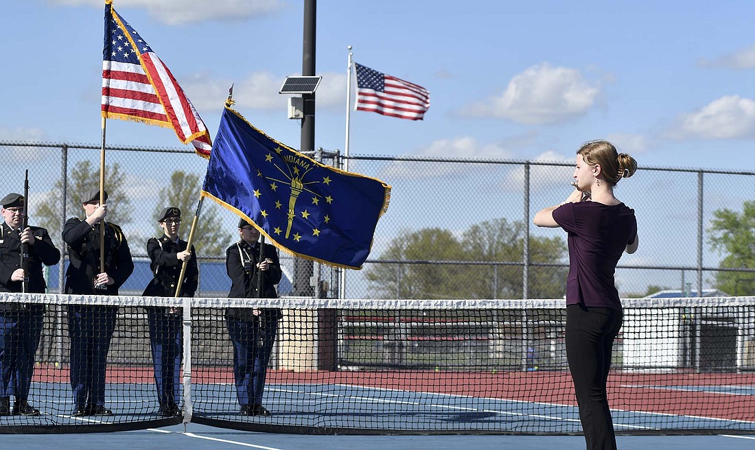 Jay County High School senior Hannah Boggs plays The Star-Spangled Banner on the flute with the Jay County ROTC presenting the colors prior to the Patriots’ girls tennis match and softball game Tuesday. The JCHS tennis program announced a donation prior to the match and donated to the band boosters previously as a thank you for Tuesday and to support what they do for the youth of Jay County. (The Commercial Review/Andrew Balko)