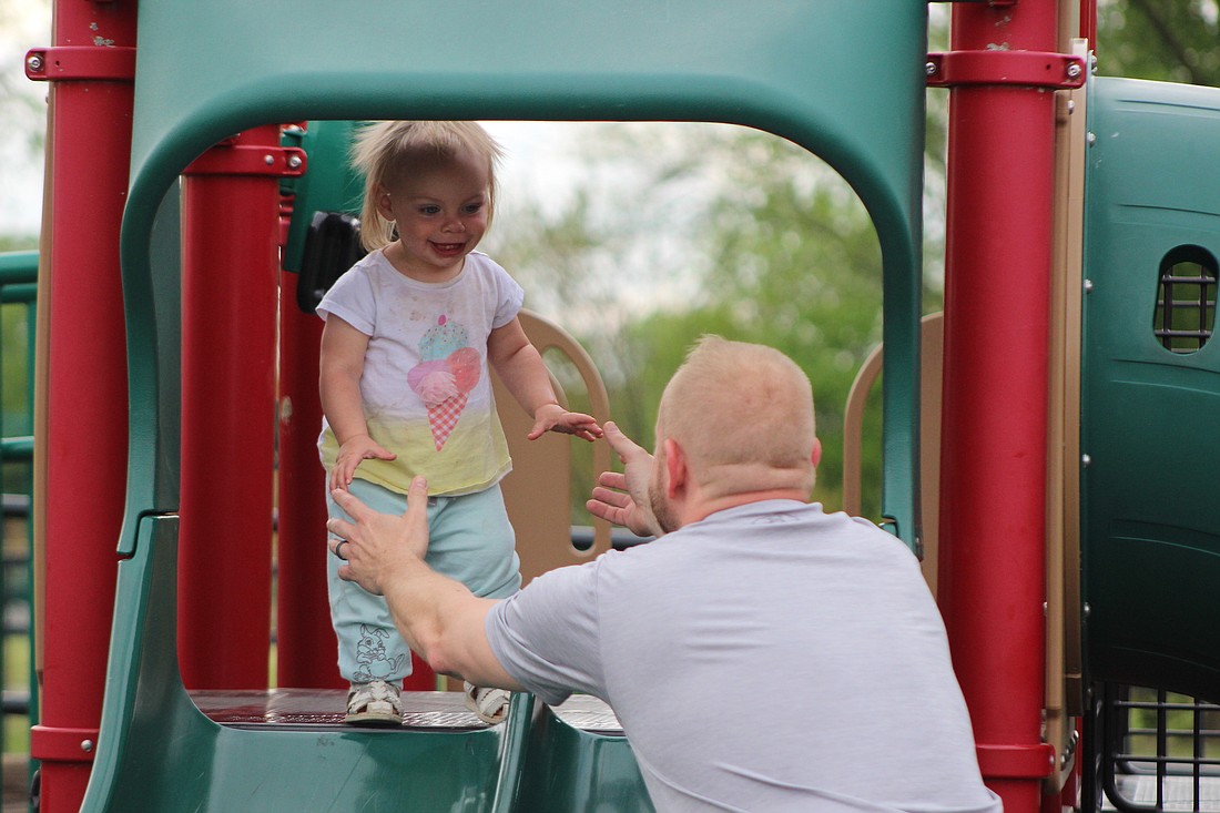 Violet Vogel, 1, walks to her father before going down the slide Friday at Hudson Family Park. Temperatures ranged in the mid to low 70s Friday afternoon with a slight breeze. Today’s forecast shows a 40% chance of rain and thunderstorms with showers continuing into Sunday. (The Commercial Review/Bailey Cline)