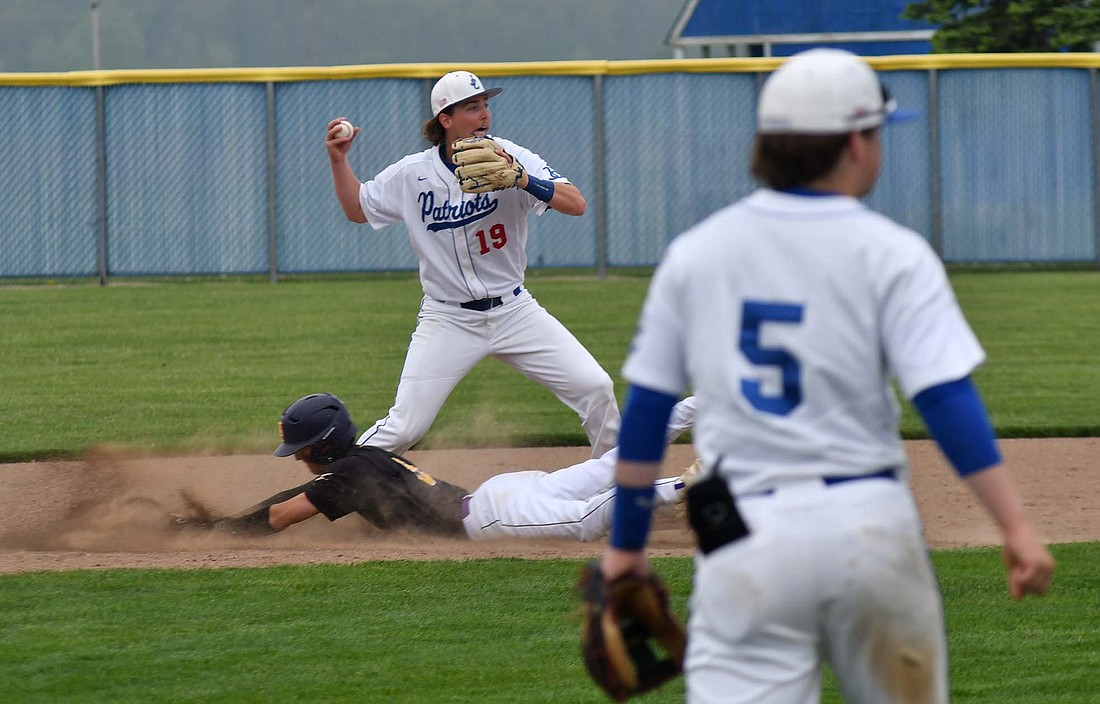 Jay County High School shortstop Sam Myers tries to turn a double play in the first game of a doubleheader against Class 2A No. 1 Hagerstown on Saturday. The Patriots dropped both games of the doubleheader only after forcing extra innings against the Tigers. (The Commercial Review/Andrew Balko)